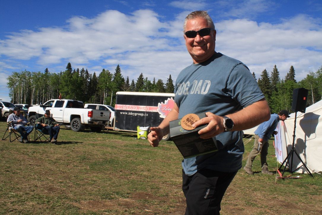 A man is standing in a field holding a hat.
