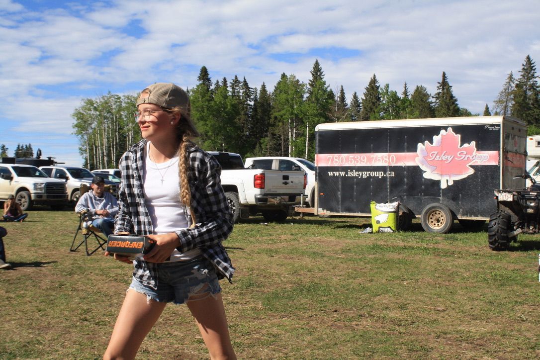 A woman is standing in a field holding a remote control.
