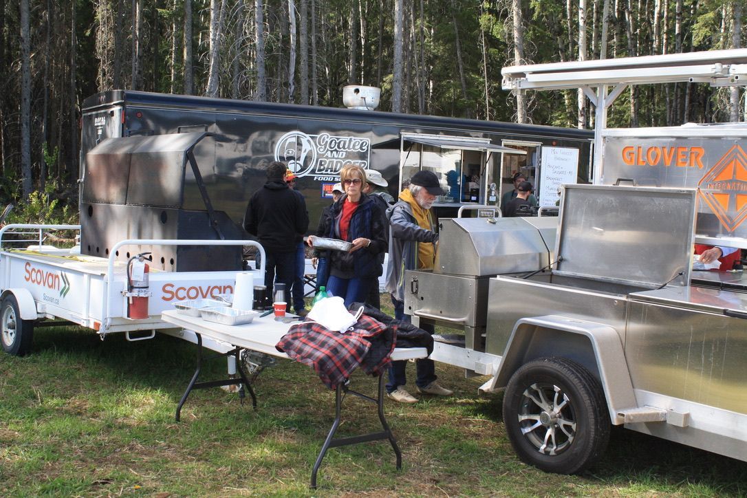 A group of people are standing around a table in front of a trailer.
