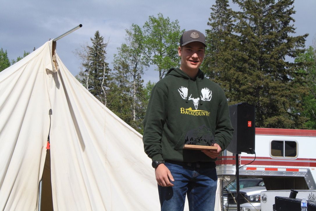 A man standing in front of a tent holding a plaque