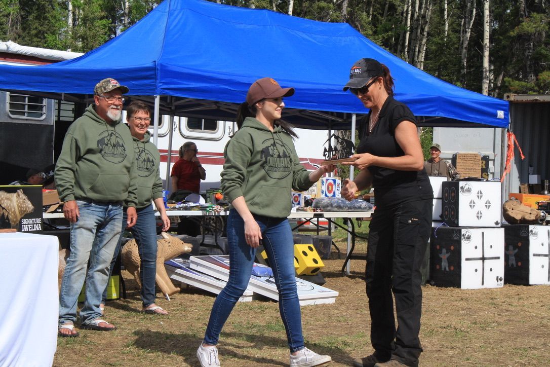 A group of people are standing under a blue tent.