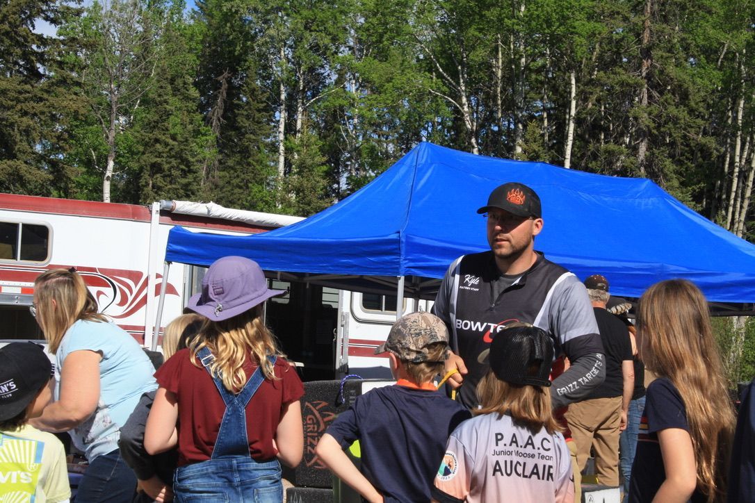 A group of people are standing under a blue tent.