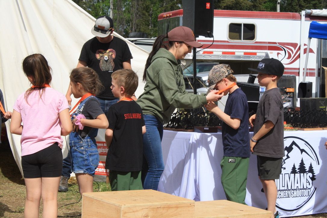 A group of children are standing around a table with a sign that says imms on it