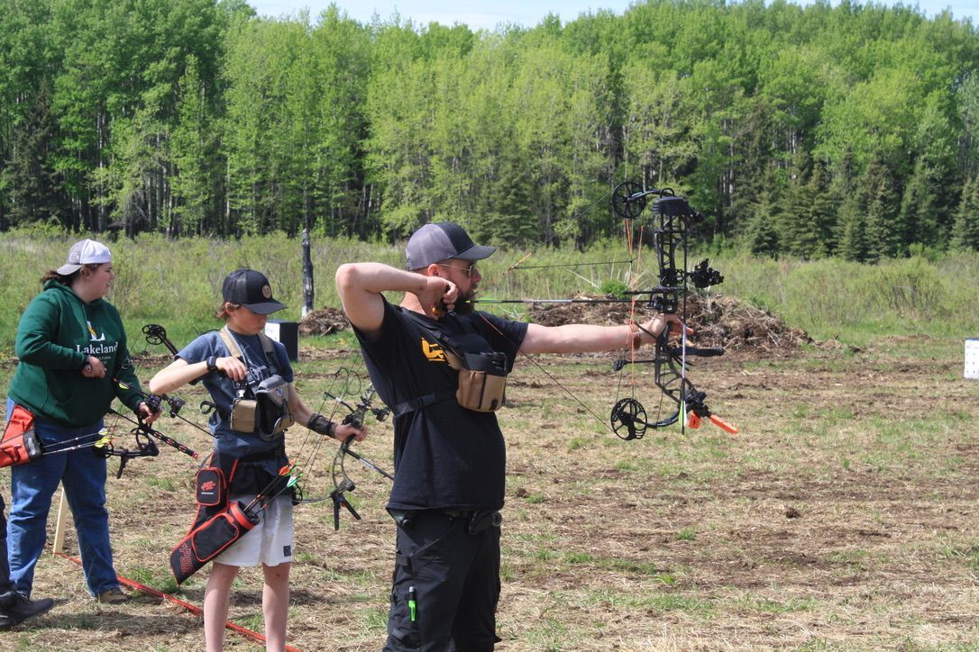 A group of people are standing in a field holding bows and arrows.