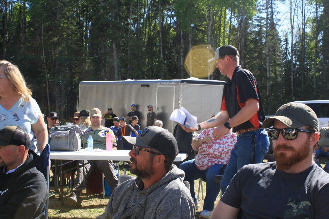 A group of people are sitting around a table in the woods.