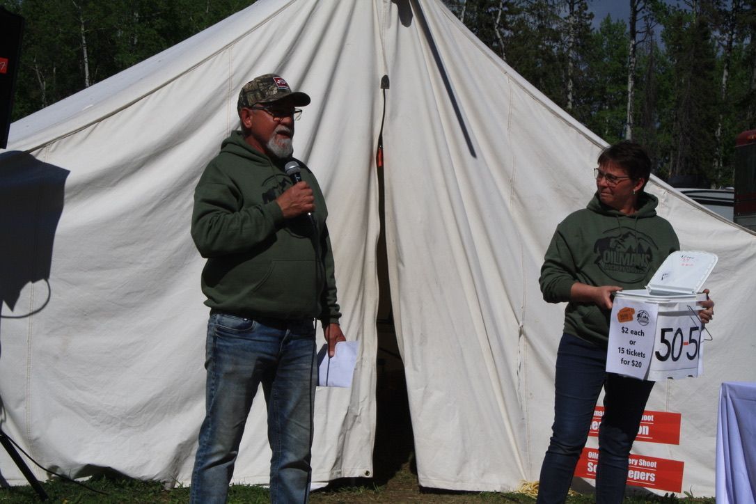 A man stands in front of a tent while a woman holds a sign that says 505