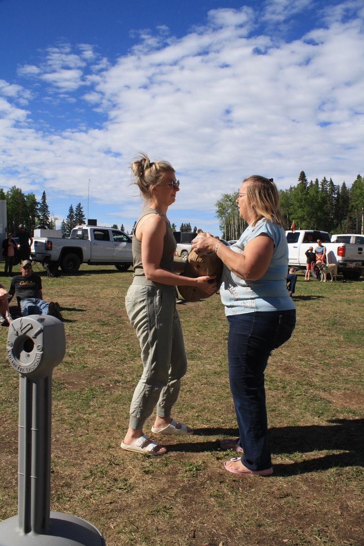 Two women are standing in a field talking to each other.