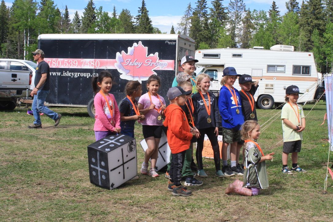 A group of children are standing in a field in front of a trailer.