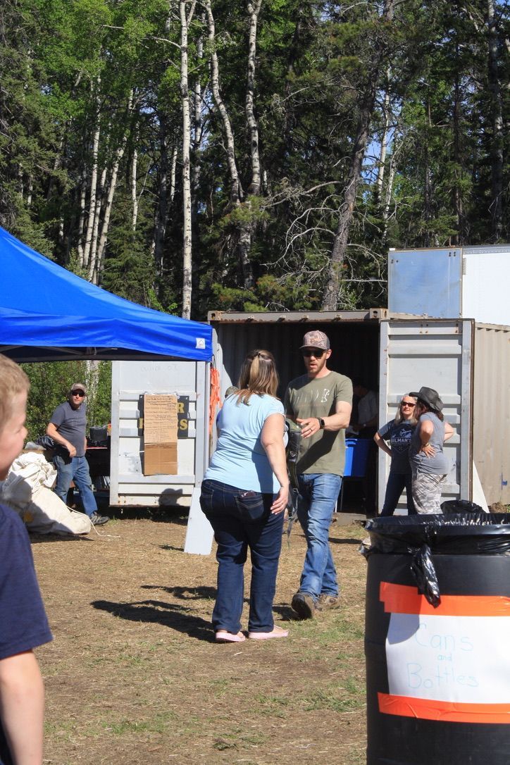 A group of people standing in a field with a trash can in the foreground