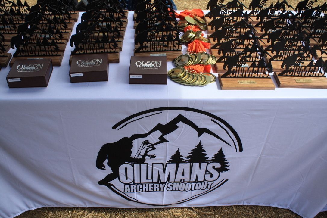 A table with trophies on it that says oilmans archery & hunting
