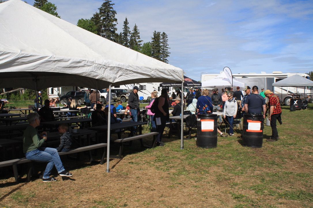 A group of people are sitting under tents in a field.