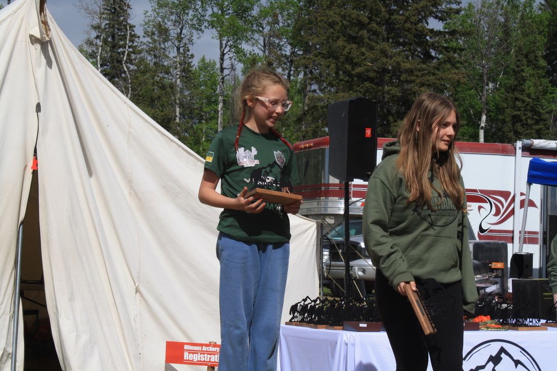 Two girls are standing in front of a white tent