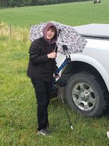 A man is standing next to a truck holding an umbrella.