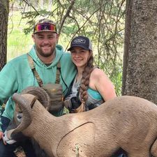 A man and a woman are standing next to a statue of a ram.