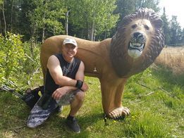 A man is kneeling next to a statue of a lion.