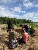 A group of people are standing around a deer in a field.
