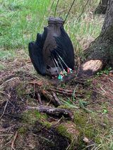 A bag of arrows is sitting on the ground next to a tree.