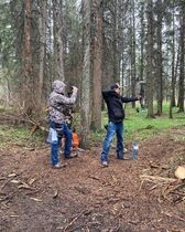 Two people are standing in the woods holding bows and arrows.