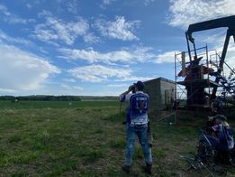 A man is standing in a field looking through binoculars.