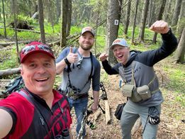 Three men are taking a selfie in the woods.