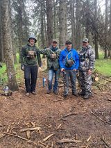 A group of men are standing next to each other in the woods.
