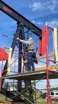 A man is standing on a scaffolding next to an oil rig.