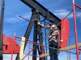 A man is standing on a scaffolding working on an oil rig.