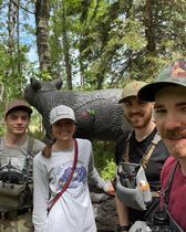 A group of people are posing for a picture in front of a statue of a bear.