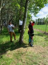 A group of people are standing under a tree in a field.
