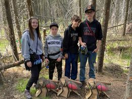 A group of young people are standing next to each other in the woods.