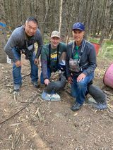 Three men are posing for a picture in the woods.