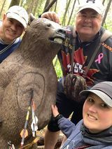 A group of people are posing for a picture with a statue of a bear.