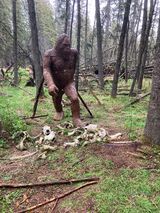 A statue of a bigfoot in the middle of a forest.