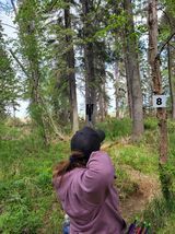 A woman is throwing a frisbee in the woods.
