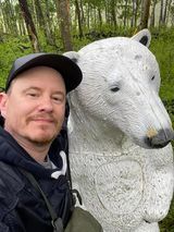 A man is standing next to a statue of a polar bear.