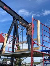 A man is standing on a scaffolding working on a bridge.
