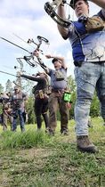 A group of people are standing in a field holding bows and arrows.