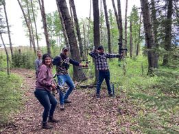 A group of people are standing in the woods holding bows and arrows.