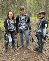 A group of people are standing next to each other in the woods holding bows and arrows.