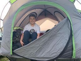 A young boy is sitting in a tent.