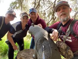 A group of people are standing around a statue of a bear.