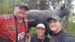 A group of people are posing for a picture in front of a statue of a bear.