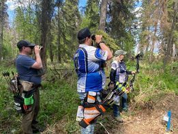 A group of people are standing in the woods with bows and arrows.