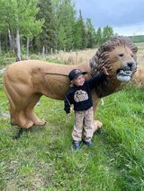 A little boy is standing next to a statue of a lion.