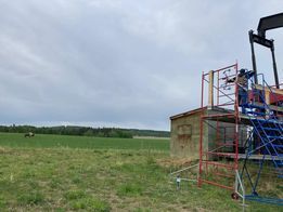 A man is standing on a scaffolding next to a building in a field.