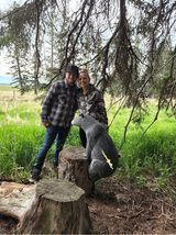 Two people are standing next to a statue of a kangaroo on a tree stump.
