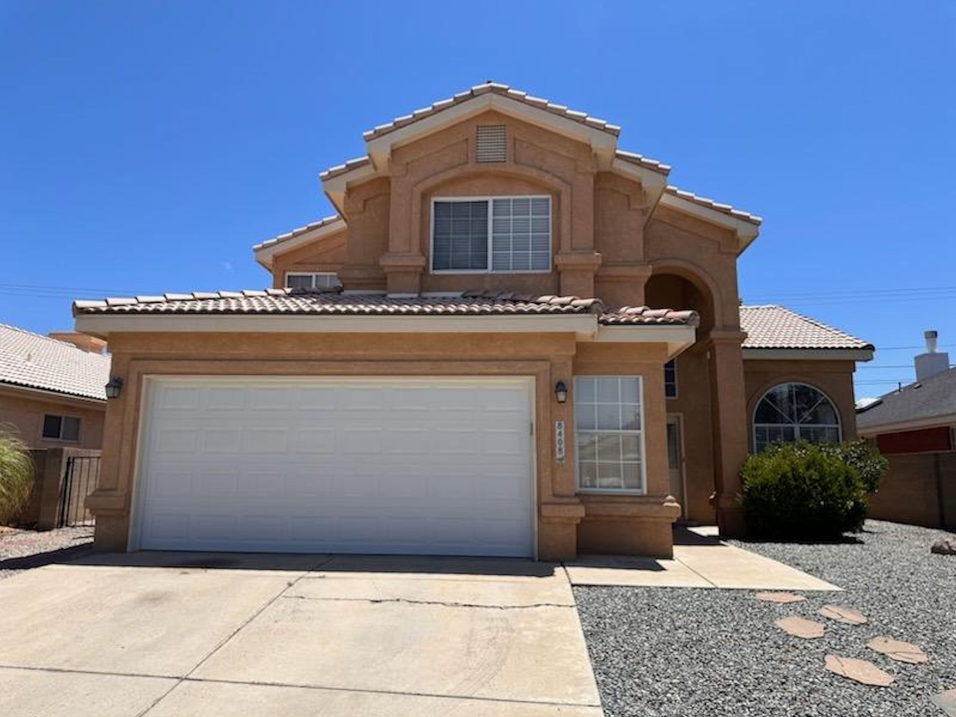 A large house with a white garage door and a blue sky in the background