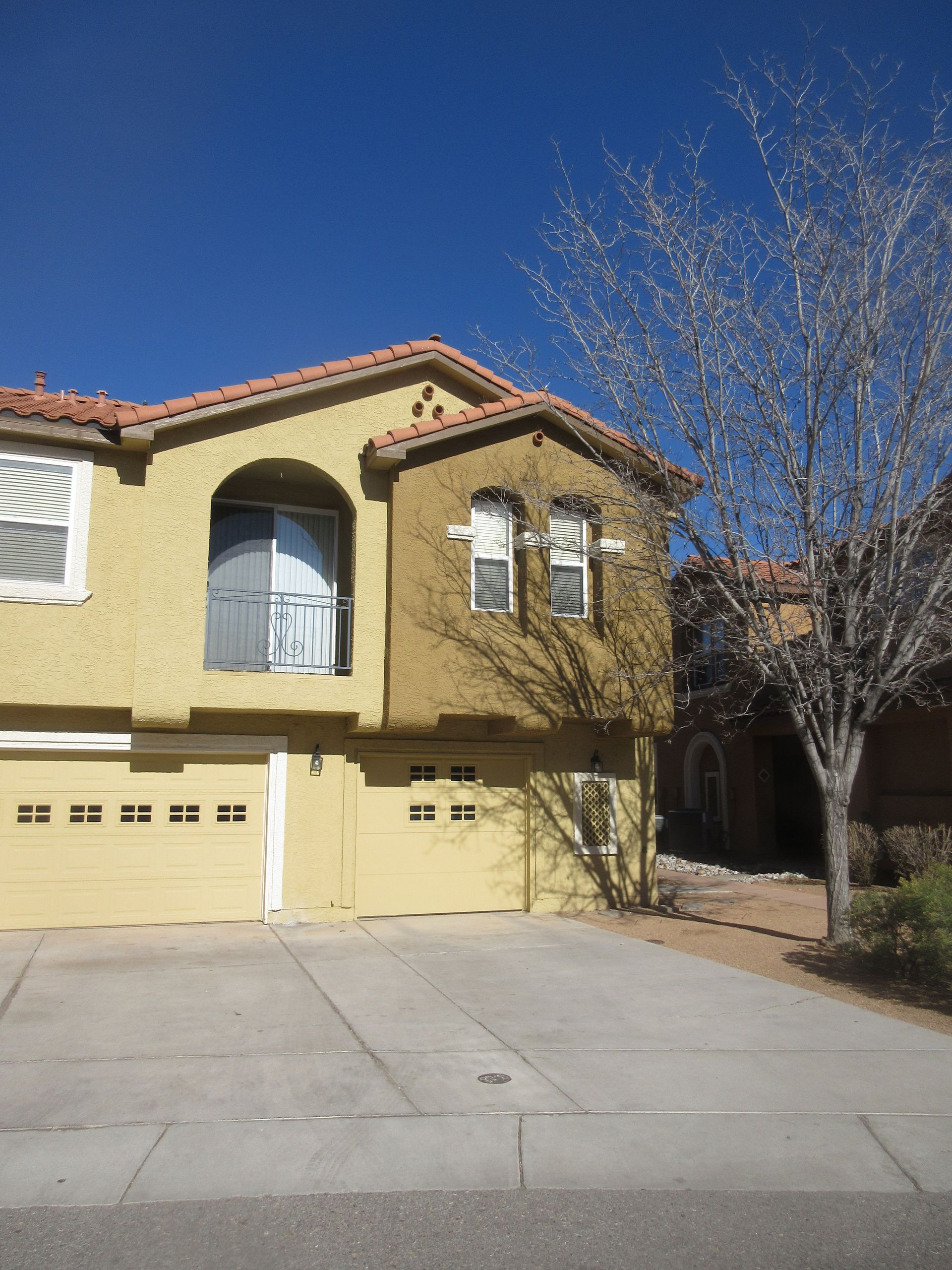 A large yellow house with a tree in front of it