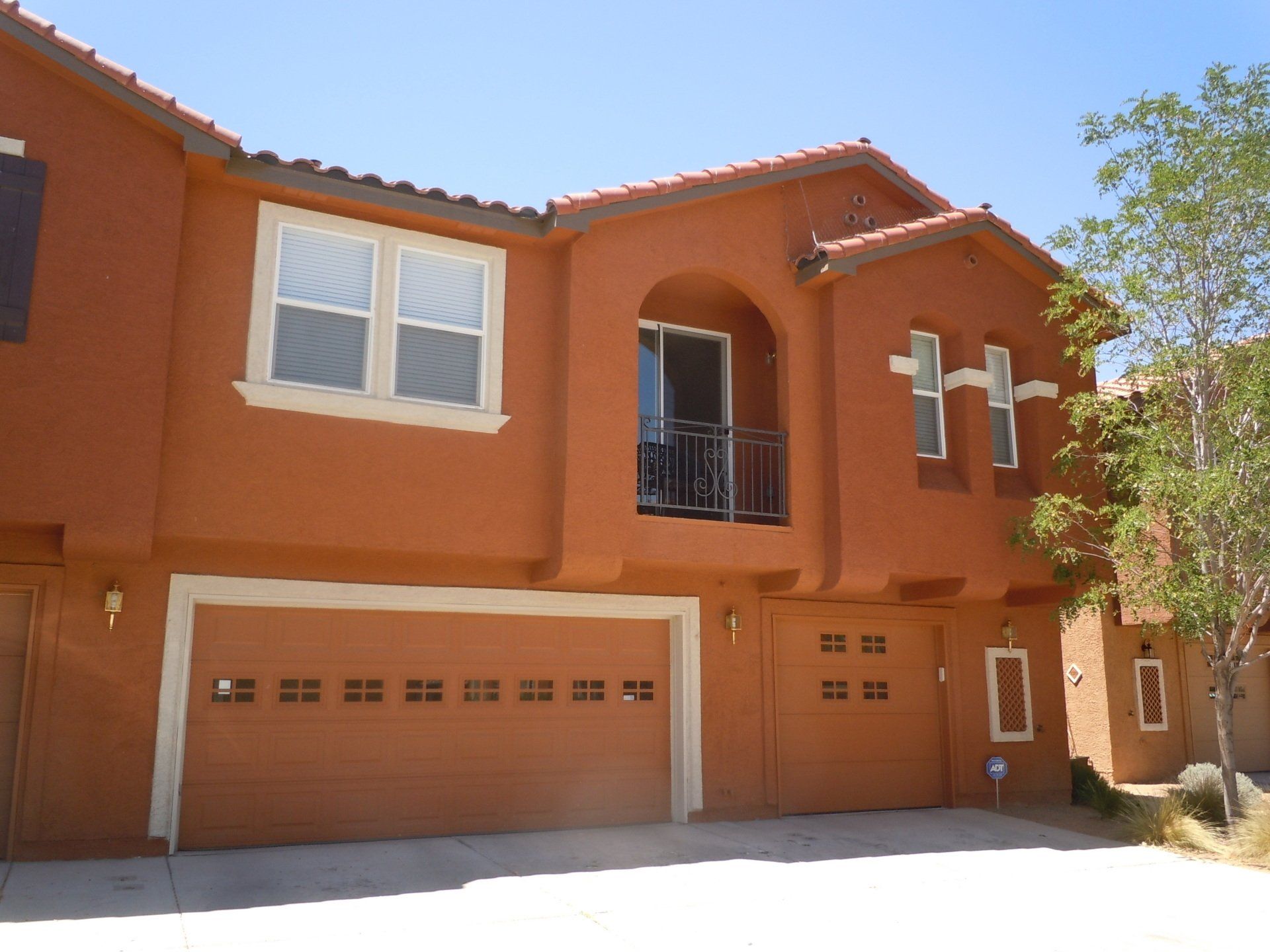 A large red house with two garage doors and a balcony