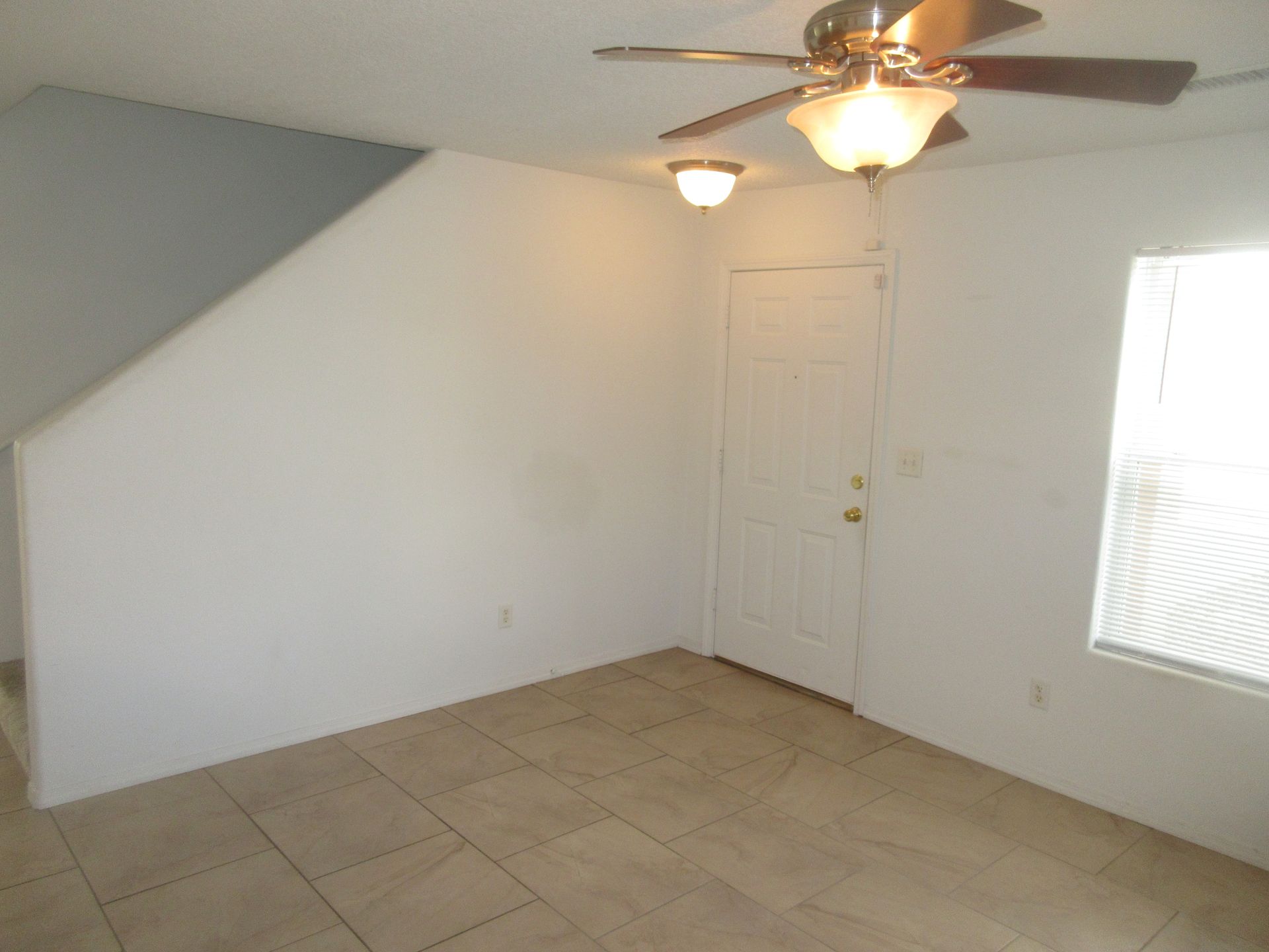 An empty room with a ceiling fan and a window